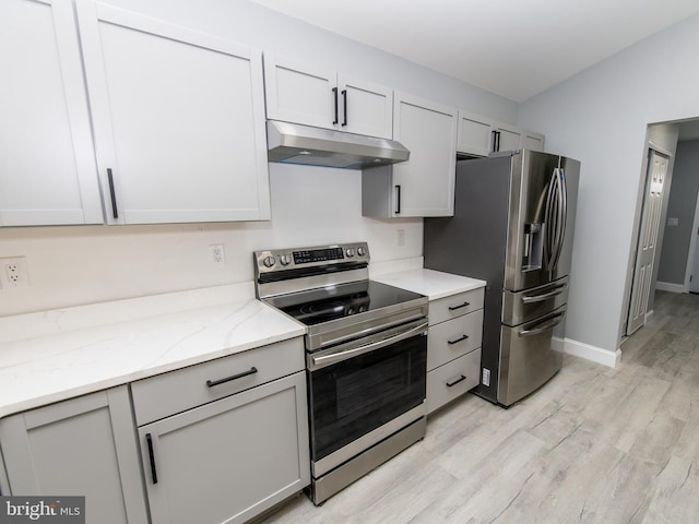 kitchen with light stone counters, appliances with stainless steel finishes, light wood-style flooring, and under cabinet range hood