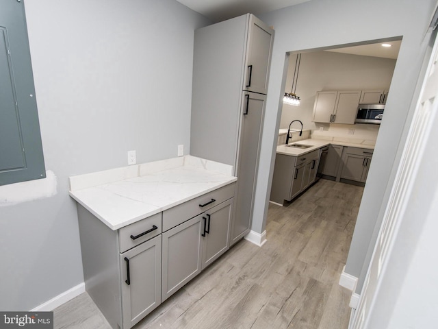 bathroom with electric panel, a sink, baseboards, and wood finished floors