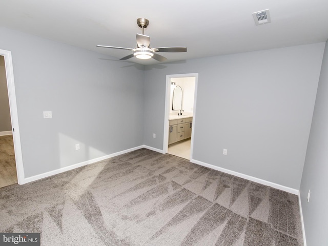 unfurnished bedroom featuring carpet, ensuite bath, visible vents, and baseboards