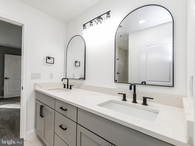 bathroom with double vanity, a sink, and baseboards