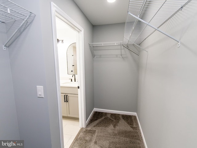 walk in closet featuring light carpet and a sink