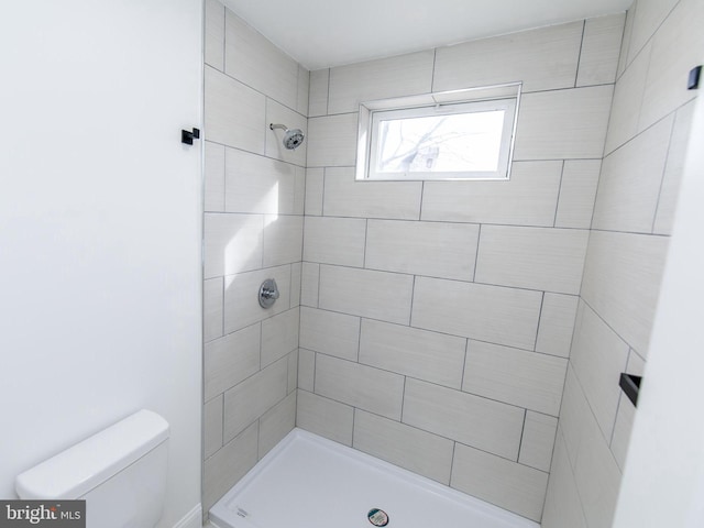 bathroom featuring tiled shower and toilet