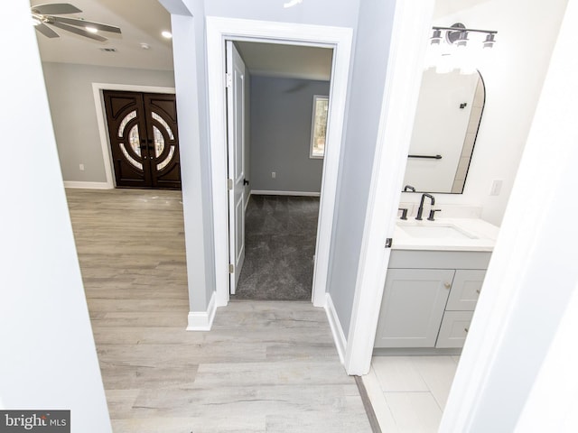 bathroom featuring ceiling fan, baseboards, wood finished floors, and vanity