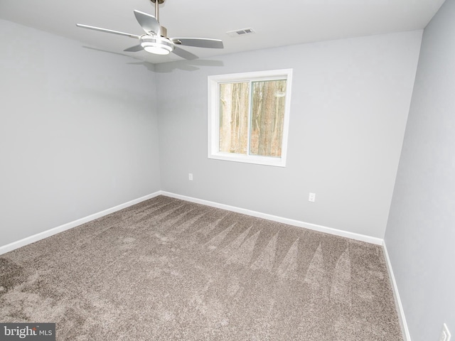 carpeted spare room with baseboards, visible vents, and ceiling fan