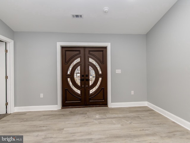 foyer entrance featuring light wood-type flooring, baseboards, visible vents, and french doors