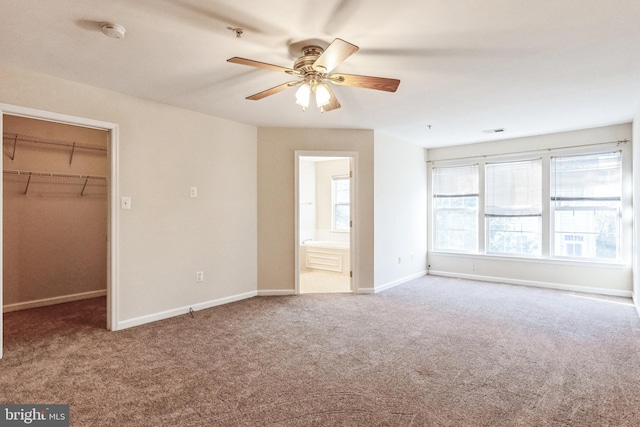 interior space with ensuite bathroom, carpet flooring, ceiling fan, a spacious closet, and a closet