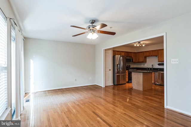 kitchen featuring sink, ceiling fan, a kitchen island, wood-type flooring, and stainless steel appliances