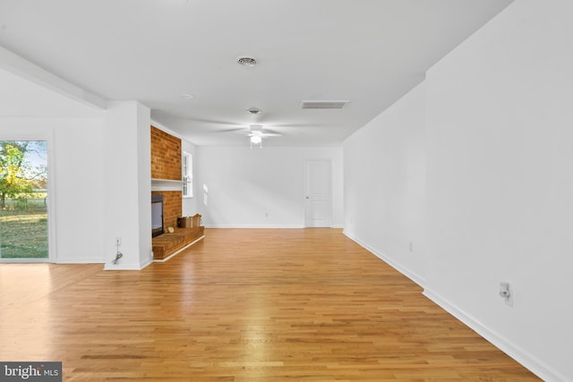 unfurnished living room featuring ceiling fan, a fireplace, and light wood-type flooring