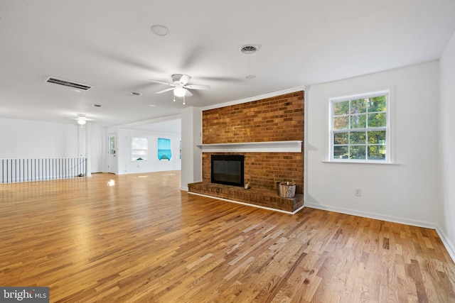 unfurnished living room with ceiling fan, light hardwood / wood-style flooring, and a brick fireplace