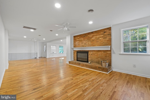 unfurnished living room with ceiling fan, light hardwood / wood-style flooring, and a brick fireplace