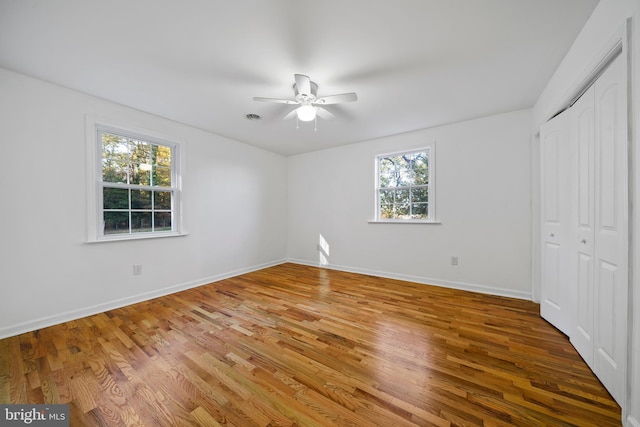 unfurnished bedroom with hardwood / wood-style flooring, ceiling fan, and multiple windows