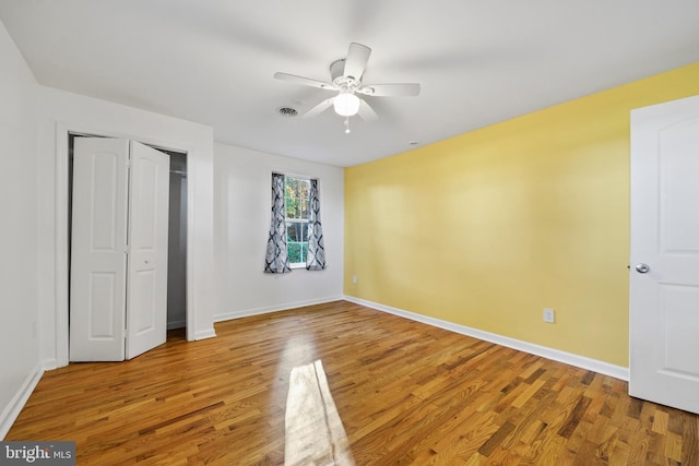 unfurnished bedroom with wood-type flooring, a closet, and ceiling fan