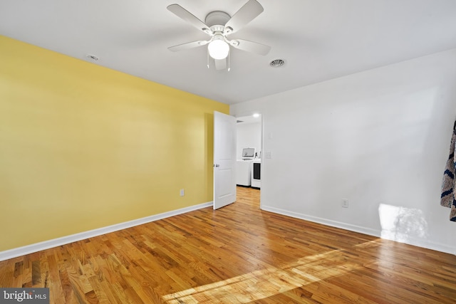 empty room with ceiling fan, light wood-type flooring, and washer / clothes dryer