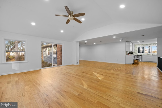 unfurnished living room with ceiling fan, vaulted ceiling, and light wood-type flooring