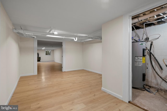 basement featuring light wood-type flooring and electric water heater