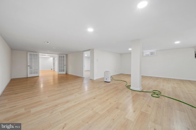 basement featuring french doors and light hardwood / wood-style floors