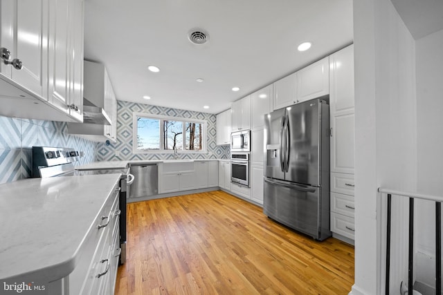 kitchen with decorative backsplash, stainless steel appliances, sink, light hardwood / wood-style flooring, and white cabinets