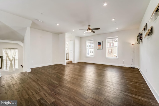 unfurnished living room featuring ceiling fan and dark wood-type flooring