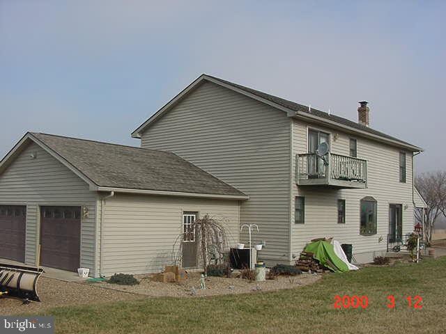 rear view of house with a balcony, a garage, and a lawn