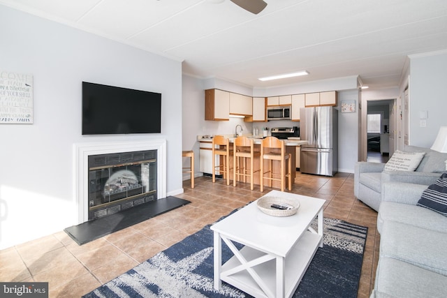 living room featuring ceiling fan, sink, light tile patterned flooring, and ornamental molding