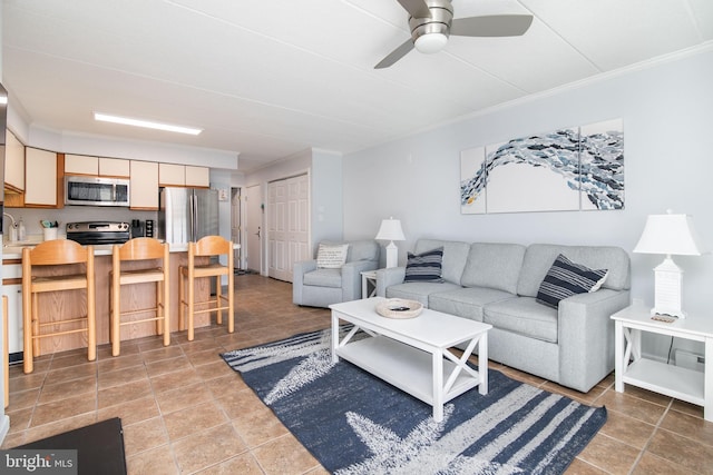 living room featuring tile patterned flooring, ceiling fan, and crown molding