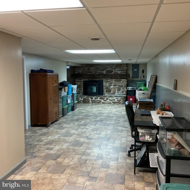 basement with a wood stove and a paneled ceiling