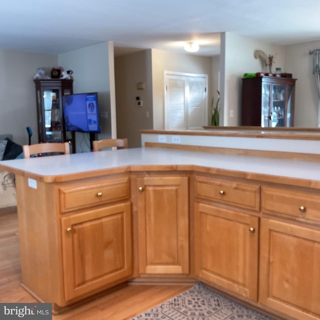 kitchen featuring kitchen peninsula, a breakfast bar area, and light wood-type flooring