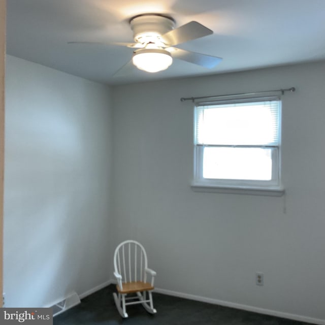 spare room featuring dark colored carpet and ceiling fan