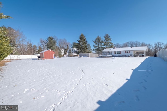 yard layered in snow featuring a storage shed