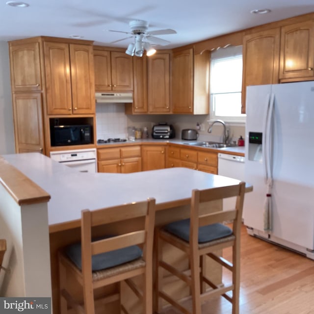kitchen featuring a kitchen breakfast bar, light hardwood / wood-style flooring, white appliances, a kitchen island, and decorative backsplash
