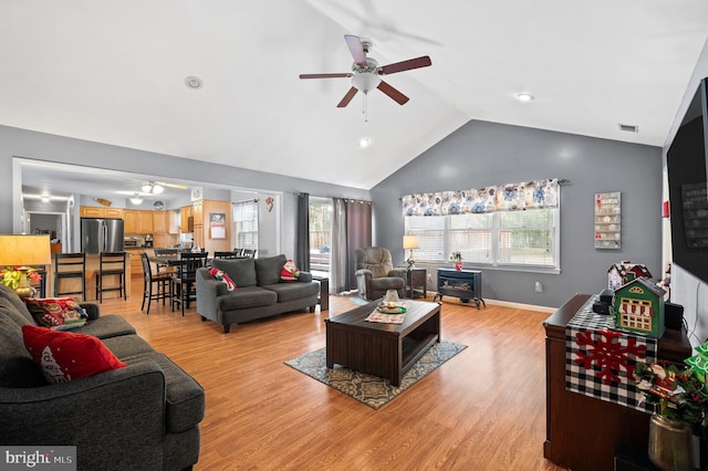 living room with ceiling fan, light hardwood / wood-style flooring, and vaulted ceiling