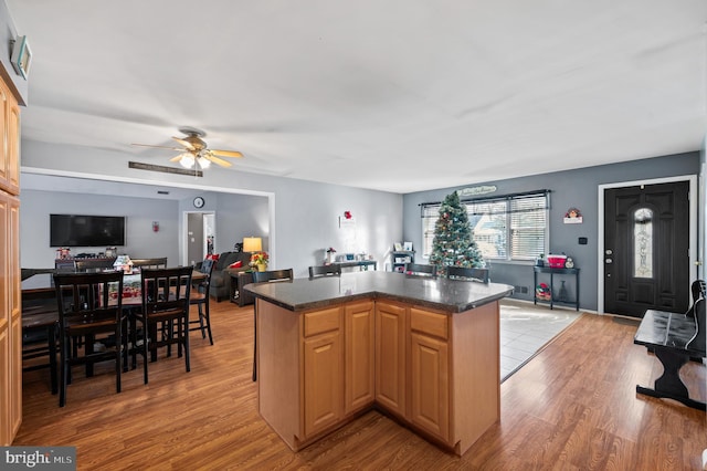 kitchen featuring ceiling fan, a kitchen island, light wood-type flooring, and light brown cabinetry