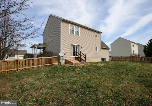 rear view of house with central AC and a lawn