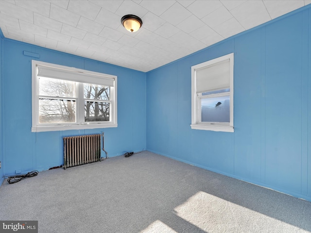 carpeted empty room featuring radiator heating unit