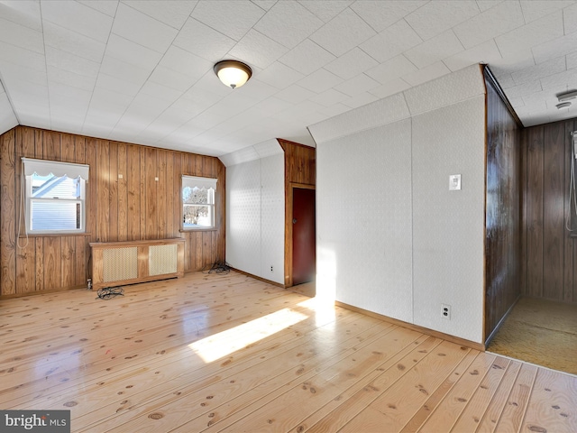 additional living space with radiator, light hardwood / wood-style floors, and vaulted ceiling