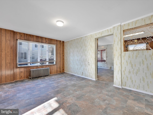 spare room featuring baseboard heating, radiator, and wooden walls