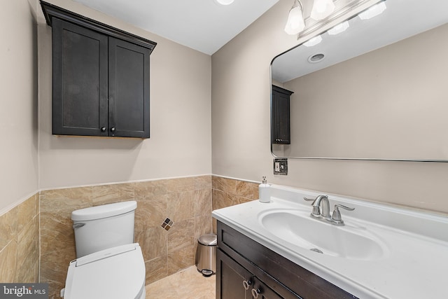 bathroom with tile walls, tile patterned flooring, vanity, and toilet