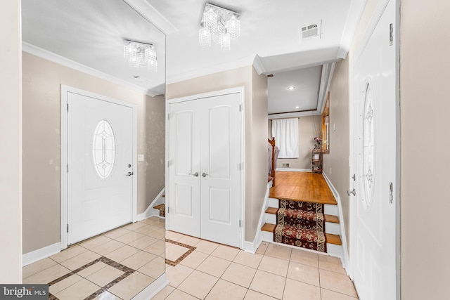 foyer featuring crown molding, a chandelier, and light tile patterned floors