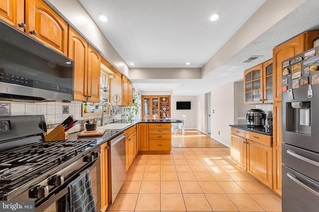 kitchen with stainless steel appliances, light tile patterned flooring, decorative backsplash, and sink