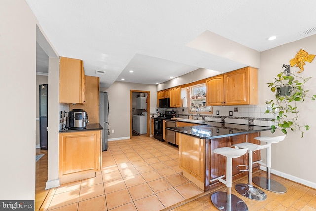 kitchen with stainless steel appliances, sink, a kitchen breakfast bar, tasteful backsplash, and kitchen peninsula