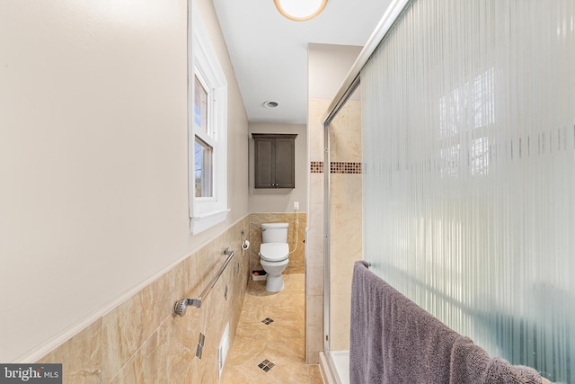 bathroom with tile walls, walk in shower, tile patterned floors, and toilet