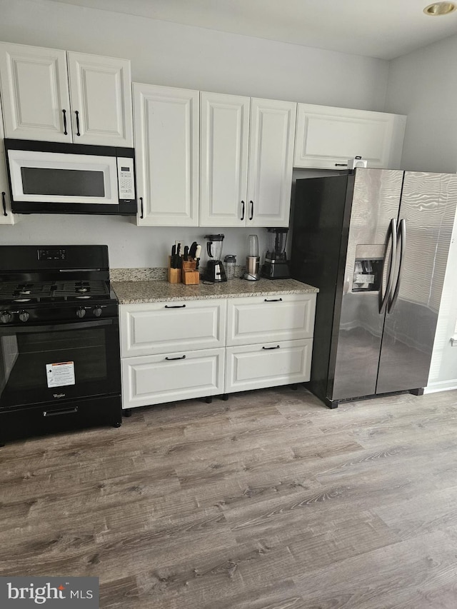 kitchen with black range with gas cooktop, white cabinetry, stainless steel refrigerator with ice dispenser, light stone countertops, and light wood-type flooring