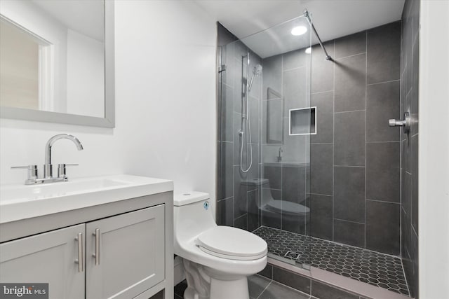 bathroom featuring tile patterned flooring, vanity, toilet, and a tile shower