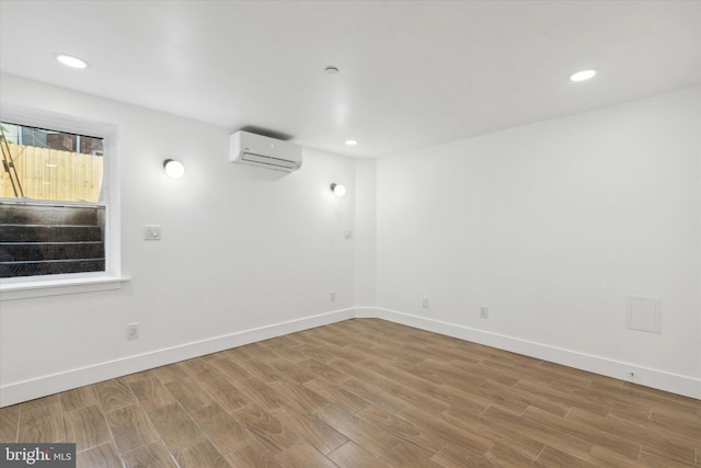 unfurnished room with a wall mounted AC and hardwood / wood-style flooring