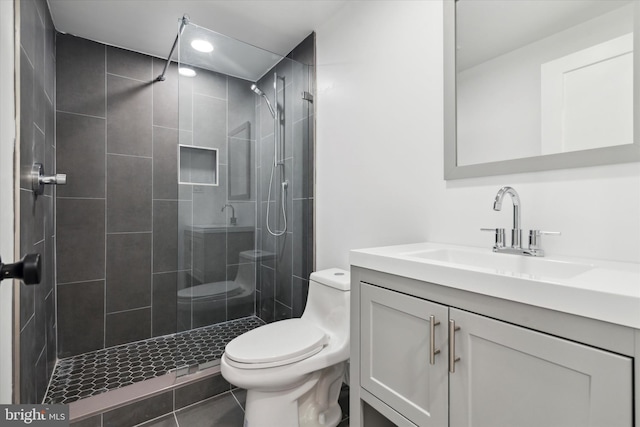 bathroom featuring a tile shower, tile patterned floors, vanity, and toilet