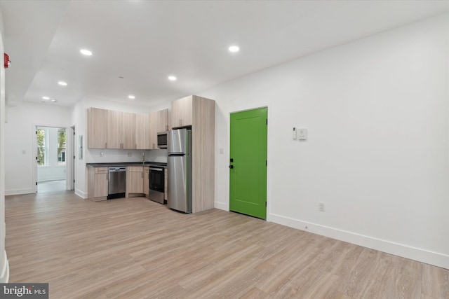 kitchen with light brown cabinetry, stainless steel appliances, and light hardwood / wood-style floors