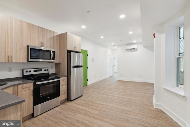 kitchen featuring light brown cabinetry, stainless steel appliances, light hardwood / wood-style flooring, and a wall mounted AC