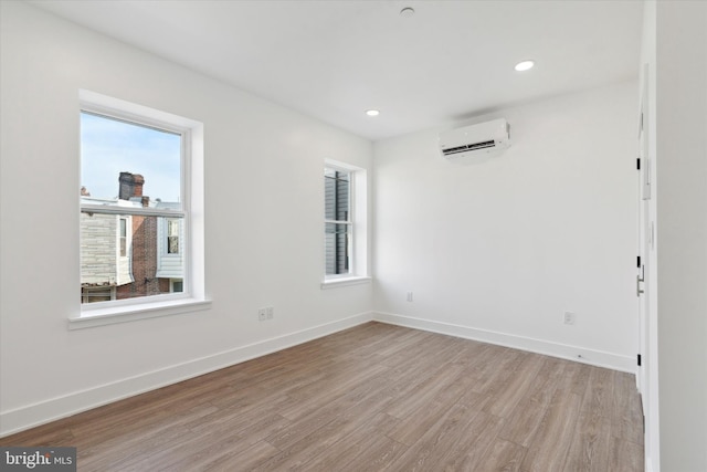 empty room with an AC wall unit and light hardwood / wood-style floors