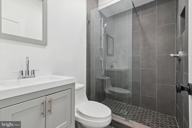 bathroom with vanity, toilet, and tiled shower