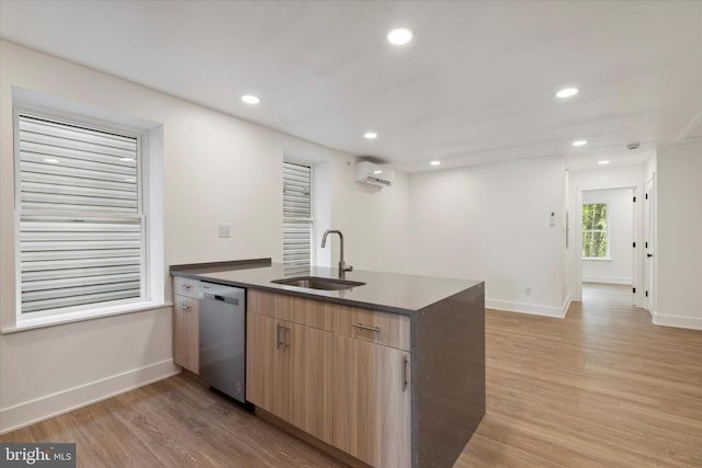 kitchen featuring stainless steel dishwasher, sink, a wall unit AC, and light hardwood / wood-style flooring